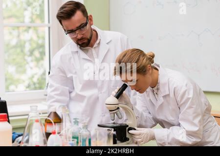 Two scientist colleagues are using microscope during research in a laboratory Stock Photo
