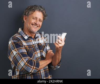 Staying in touch with technology. A portrait of a happy mature man using his smart phone. Stock Photo