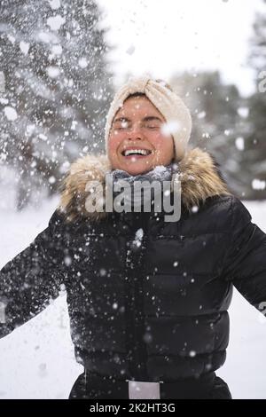 Young cheerful girl enjoying snowfall during beautiful winter day Stock Photo