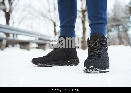 Man wearing black sneakers in winter city park Stock Photo