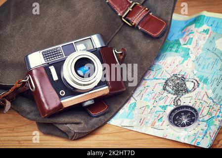 Explore, dream, discover. a camera, map, compass and bag on a wooden table. Stock Photo