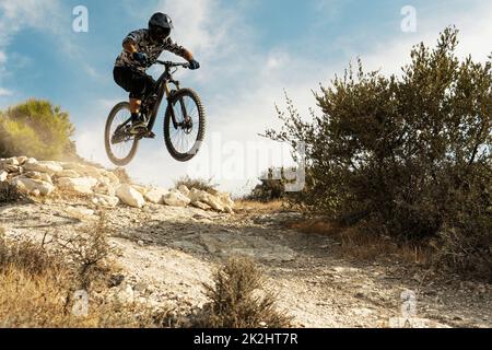 Professional bike rider jumping during downhill ride on his bicycle Stock Photo
