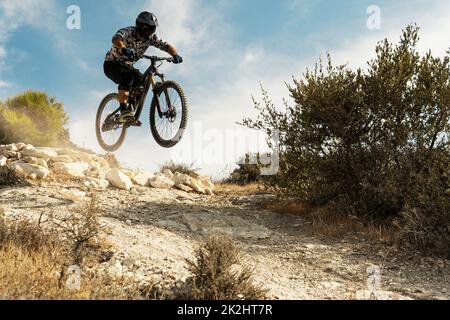 Professional bike rider jumping during downhill ride on his bicycle ...