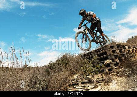 MTB bike rider jumping during downhill ride on his bicycle in mountains Stock Photo
