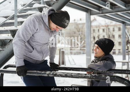 Young sportive couple during calisthenics workout during winter and snowy day Stock Photo