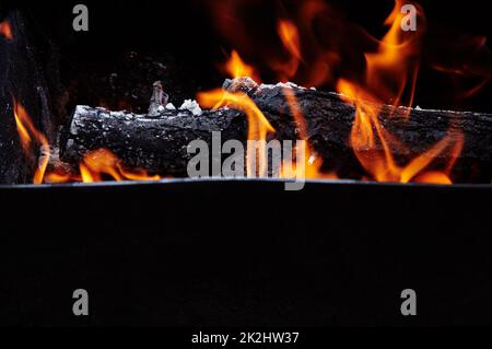 Burning red hot sparks fly from fire. Barbecue gril with glowing and flaming hot charcoal and firewood Stock Photo