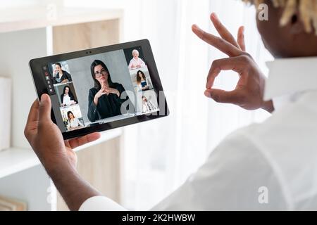Web meeting. Remote negotiation. Professional telecommuting. Satisfied business man approving agreement with okay to female partners on tablet screen Stock Photo
