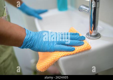 Maid cleaning wash and scrub basin in toilet at home. Stock Photo