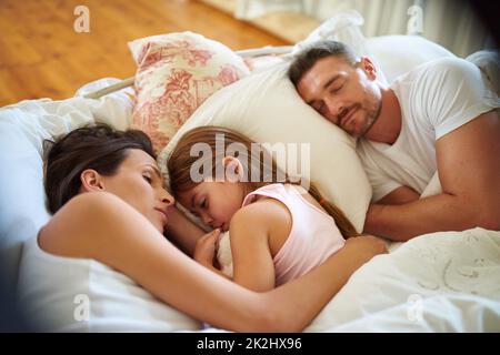 Family snuggle time. Shot of a family sleeping in bed at home. Stock Photo