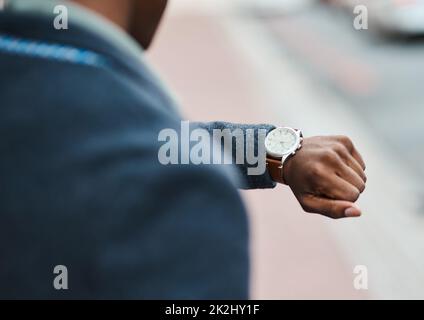 Never underestimate the value of time. Cropped shot of a businessman checking the time against an urban background. Stock Photo