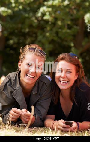 Girls together on the grass. Portrait of two young girls lying together the grass with copy space. Stock Photo