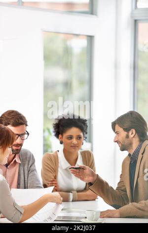 Offering a bit of business wisdom. A group of businesspeople going over some plans together in an office. Stock Photo