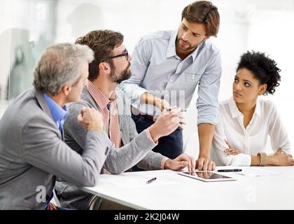 Hard working office pros. Shot of a group of young professionals working at a desk in an office. Stock Photo