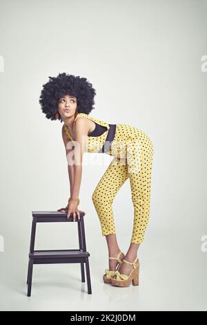 Do you think I'm groovy. A young woman wearing a 70s retro jumpsuit while pouting and striking a pose. Stock Photo