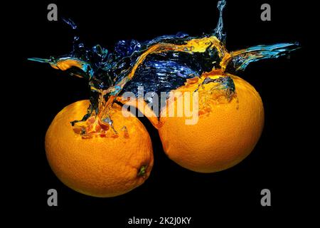 Two fresh oranges in water splashes isolated on black background. Stock Photo