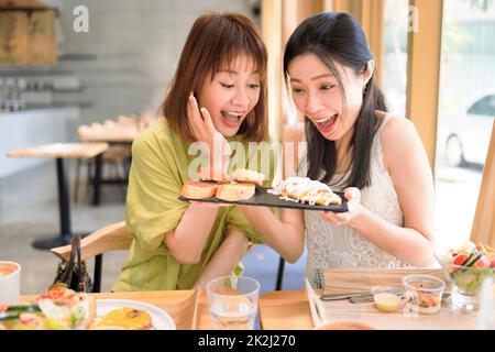 Happy girlfriends having lunch together at  restaurant Stock Photo