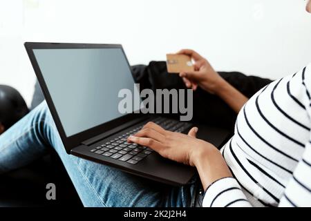 Month end shopping made so much easier. Cropped shot of a woman using a laptop and credit card on the sofa at home. Stock Photo