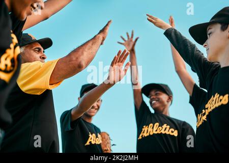 We play as one, we win as one. Shot of a team of young baseball players joining their hands together in a huddle during a game. Stock Photo