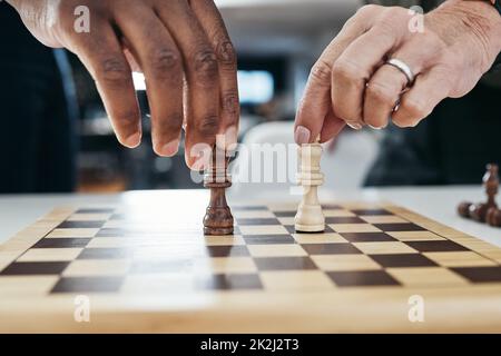 Think carefully about your next move. Shot of two unrecognizable businesspeople playing a game of chess together inside their office at work. Stock Photo