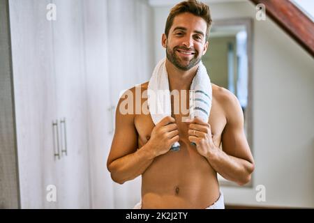 Time for a shower. Shot of a handsome young man holding a towel around his neck at home. Stock Photo