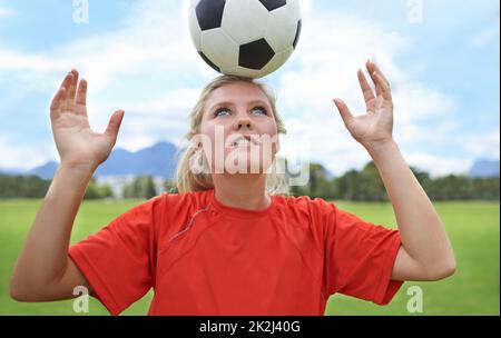 Its all about balance. Shot of a young female soccer player balancing a ball on her head. Stock Photo