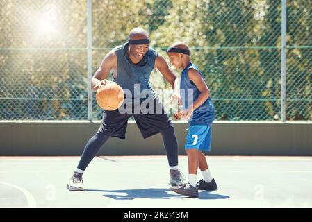 Basketball, family and teaching sport with a dad and son training on a court outside for leisure fitness and fun. Black man and kid doing exercise and Stock Photo