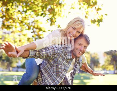 Love makes you act like kids again. a happy man piggybacking his wife. Stock Photo