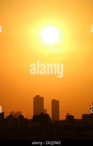 Bright sun shining on vivid orange sky over groups of skyscrapers Stock Photo