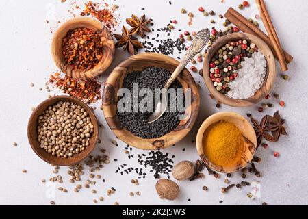 Top view of mix bright spices or seasonings in small wooden bowls as ingredient for healthy food on grey concrete background Stock Photo