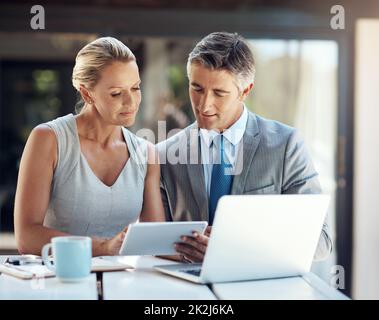 What do you think of this. a focused mature business couple looking at projections on a tablet in the office to improve their work. Stock Photo