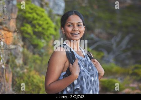 Spending some time in nature. Shot of a young woman enjoying a sunset hike on a mountain range outdoors. Stock Photo
