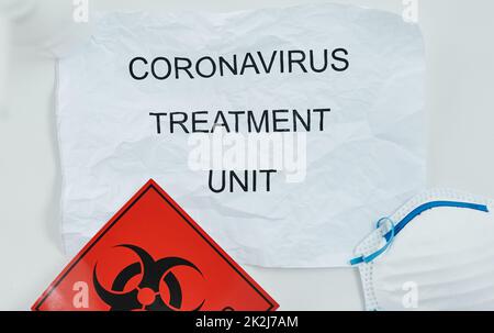 Well get you on the road to recovery. Shot of a biohazard sign, a face mask and a sign saying CORONAVIRUS TREATMENT UNIT. Stock Photo