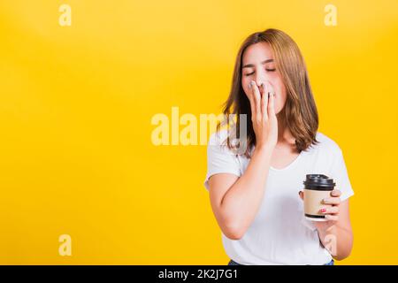 Woman Tired sleepy her cannot wake up and closes eyes holds take away cup coffee Stock Photo