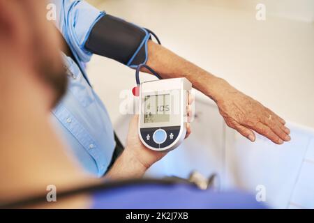 Looking good so far. Shot of an unidentifiable young doctor measuring his senior patients blood pressure. Stock Photo