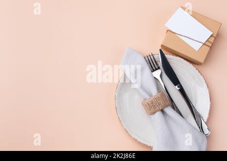 Mockup with a festive table setting and a gift on a beige background. Stock Photo