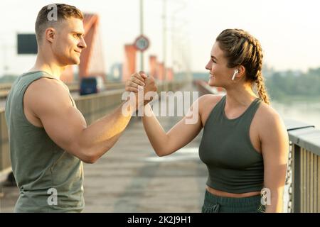 Athletic couple making handshake during fitness workout on city street Stock Photo