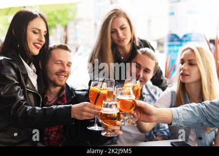 Friends celebrating and holding glasses with different alcohol drinks in a bar. Stock Photo