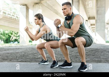 Athletic couple doing squats during street workout Stock Photo