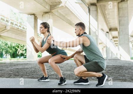 Athletic couple doing squats during street workout Stock Photo