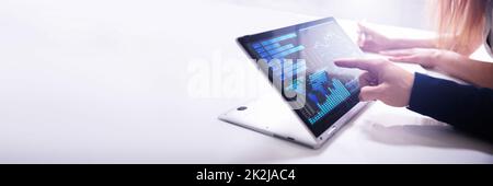 Businessman's Hand Pointing Bar Graph On Laptop Stock Photo