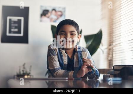 Im learning from home and I love it. Portrait of an adorable little boy completing a school assignment at home. Stock Photo