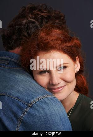 Melting in his arms. Portrait of a beautiful young woman resting her head on her boyfriends shoulder. Stock Photo