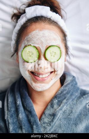 At home spa day. Shot of a young woman lying down with a beauty facial treatment on her face. Stock Photo