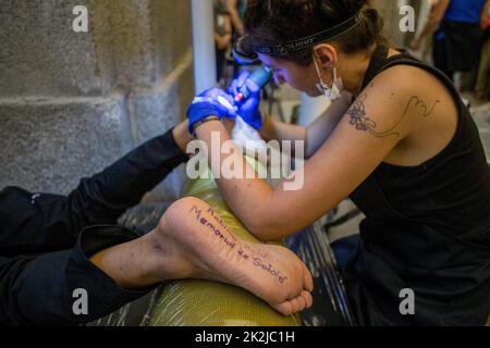 A woman tattoos the feet of the Guatemalan indigenous artist Benvenuto Chavajay during the performance entitled 'Souls in return (Popol Wuj)' inside the Reina Sofia national museum in Madrid. The performance consisted of tattooing the names of the four Mayan sacred books on the soles of the feet: Popol Wuj, Sololá Memorial, Chilam Balam and Rabinal Achí. According to Mayan belief, beauty and memory are found in the feet. This project seeks to initiate the application process before the competent authorities to return the Popol Wuj, which is currently part of the collection of the Newberry Libr Stock Photo