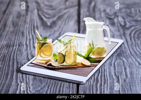 Jug and cans of lemonade on the screen of tablet computer Stock Photo