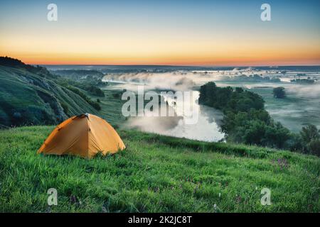 Orange tourist tent on hillside Stock Photo