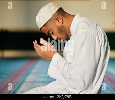 Faith can move mountains. Shot of a young muslim male praying in a mosque. Stock Photo