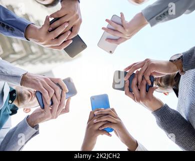 Connecting faster for the best way forward. Shot of a group of unrecognisable businesspeople using their cellphones together at and outside meeting. Stock Photo