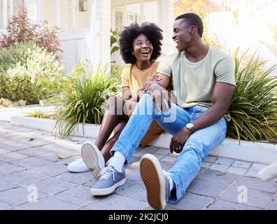 Laughing together is a love language. Shot of a young couple moving into their new house. Stock Photo
