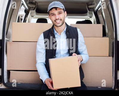 On my way to drop-off the next box. Portrait of a young delivery man loading boxes from a van. Stock Photo